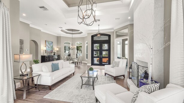 A spacious living room with a white sofa, a glass coffee table, and a chandelier.