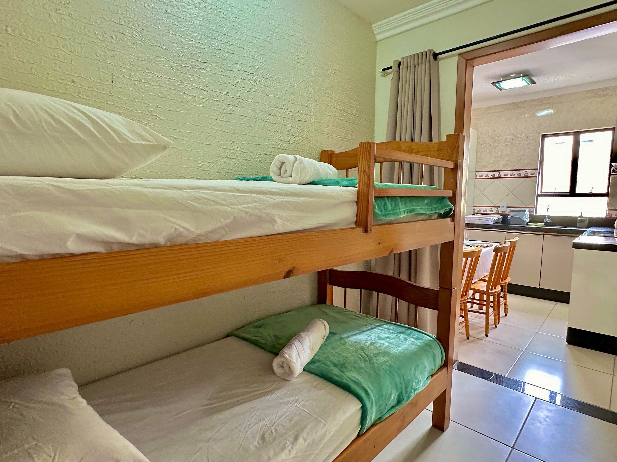 A bunk bed room with a kitchen area visible through an open door.