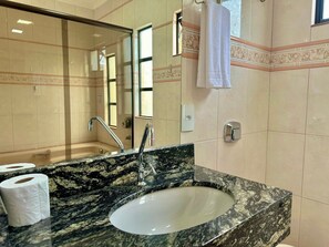 A bathroom with a marble sink, two faucets, a mirror, a towel rack, and a toilet paper holder. - Residencial Falcão (Bombinhas)