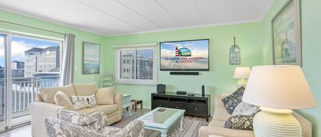 A living room with a sofa, armchair, coffee table, and a TV mounted on the wall.