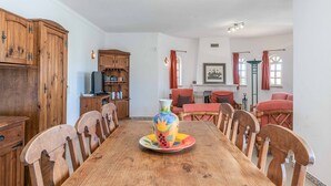 A dining room with a wooden table, chairs, a colorful vase centerpiece, and wooden cabinets. - Villa Noras - Three Bedroom Villa, Sleeps 6 (Albufeira)