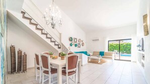 Un vaste espace de vie comprenant un escalier, une table à manger avec des chaises, un canapé et une vue sur une piscine.