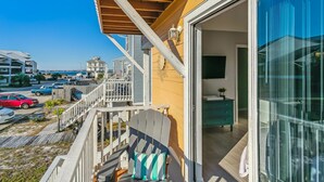 Une propriété située en bord de mer, dotée d’une terrasse en bois, d’une grande porte-fenêtre coulissante et offrant une vue sur la mer.