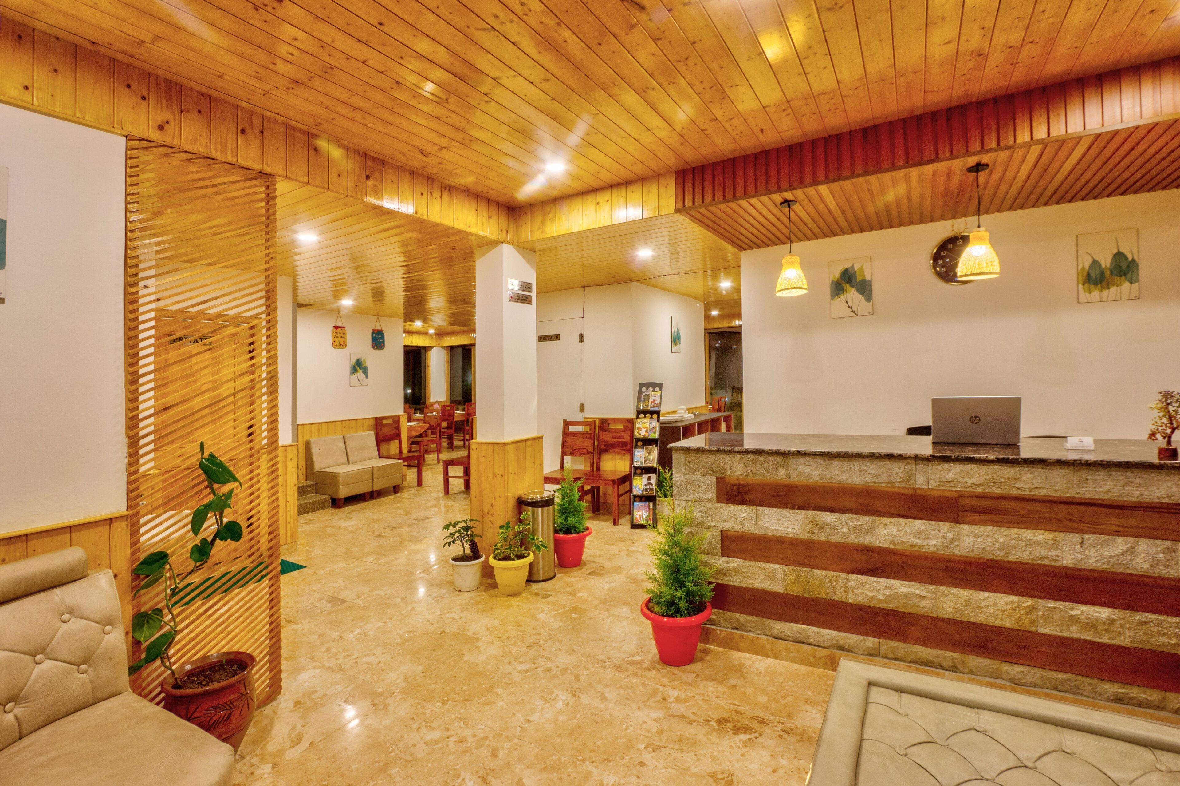 A reception area with a wooden ceiling, a reception desk, and several potted plants.