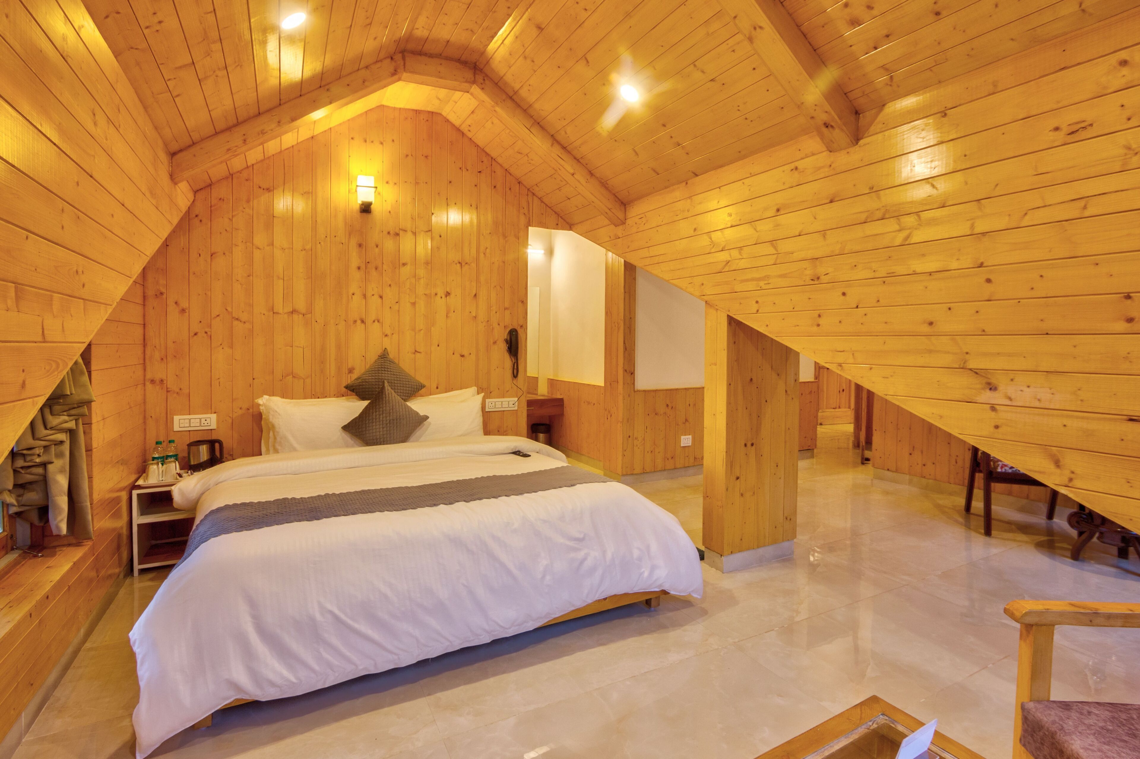 A cozy, wooden-paneled bedroom with a large bed, bedside tables, and a nightstand.
