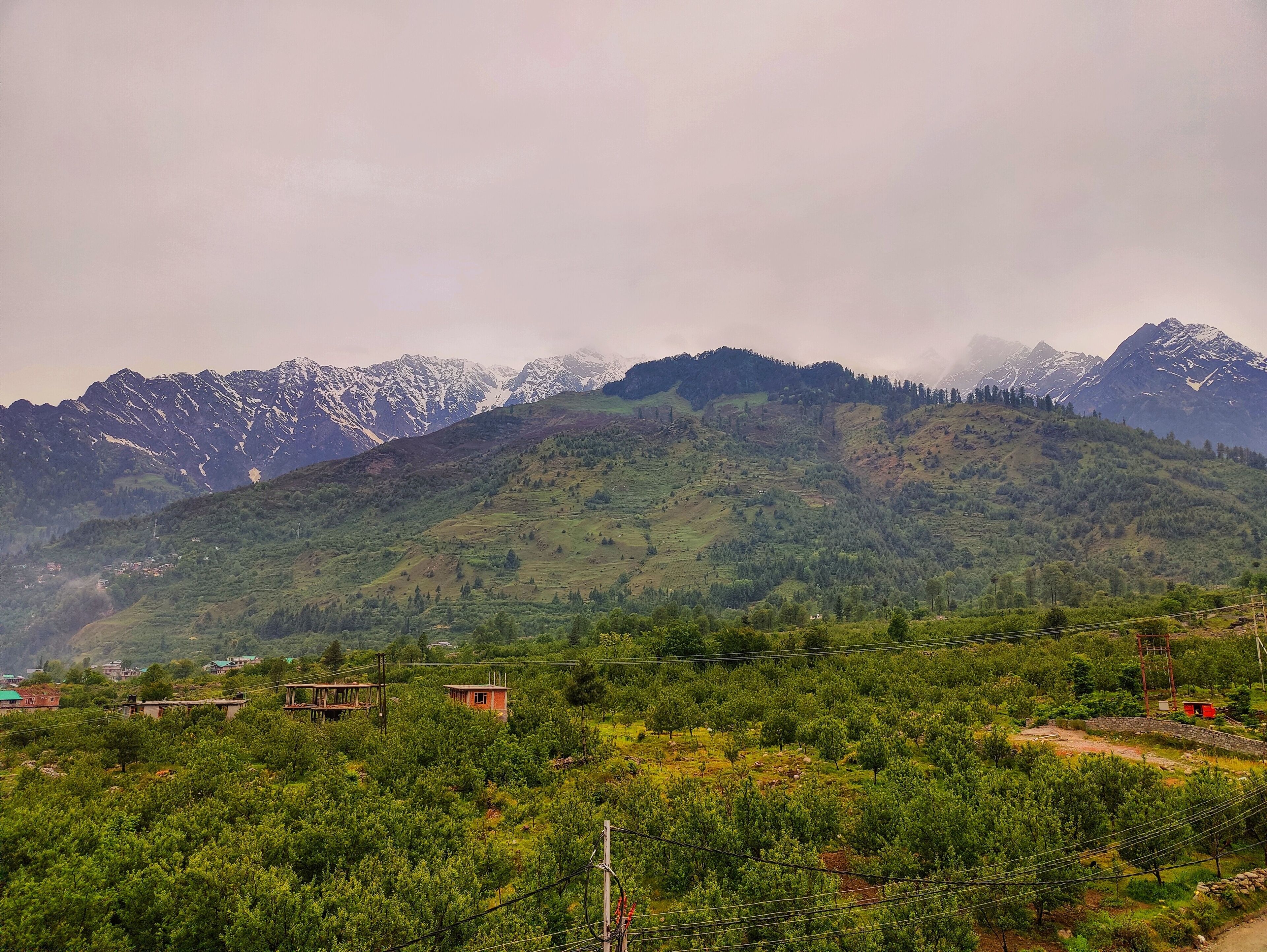 A mountainous landscape with a valley, houses, and a red structure.