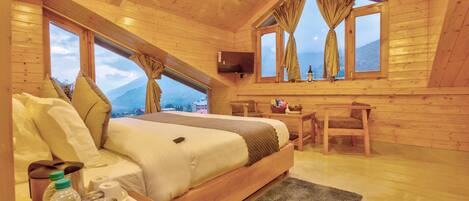 Dormitorio de una cabaña de madera con una cama, un escritorio y un televisor.
