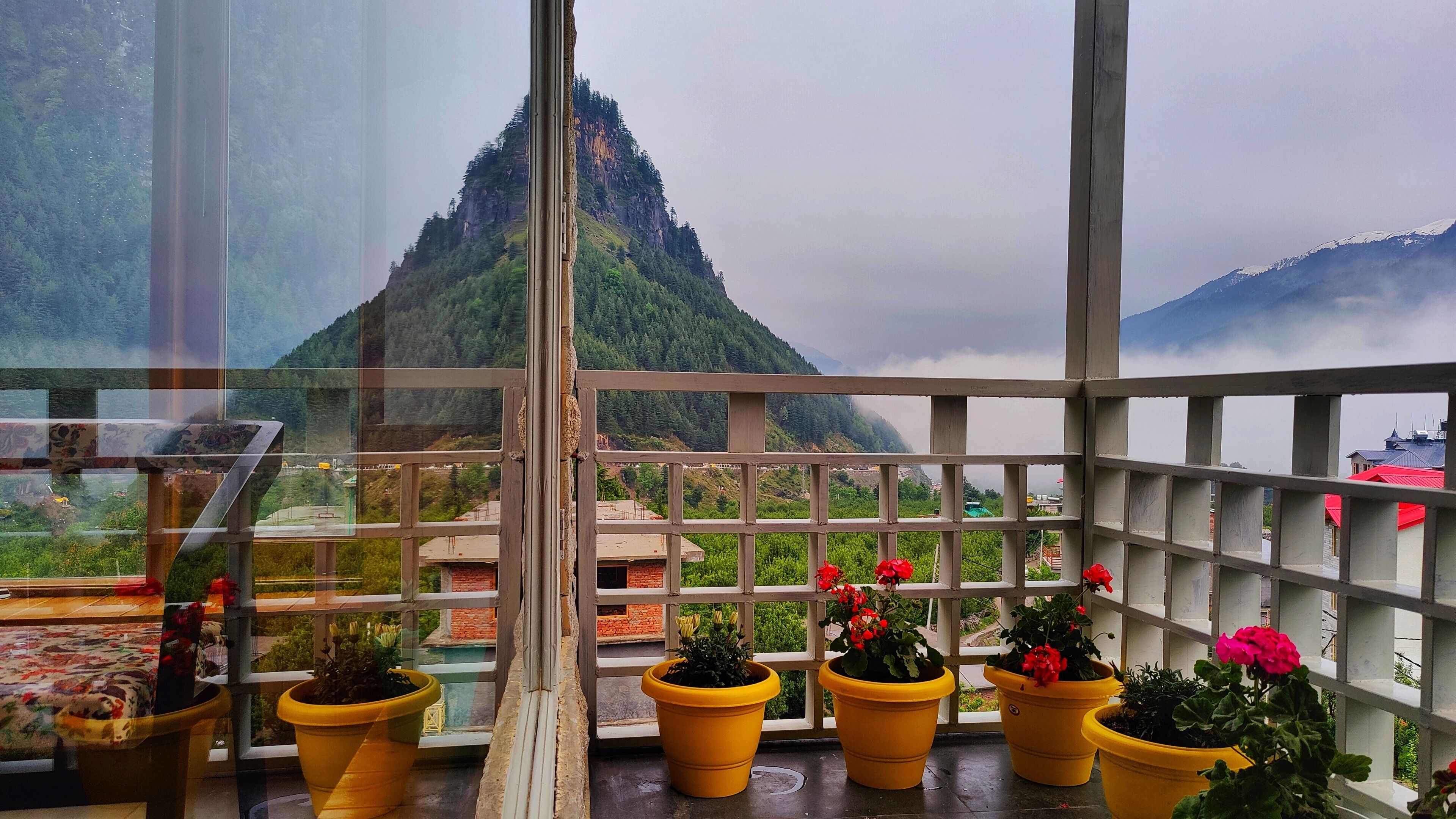 Ein Balkon mit gelben Blumentöpfen und Blick auf einen Berg.