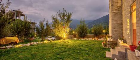 A stone building with a well-maintained lawn, outdoor lighting, and a view of mountains in the background.
