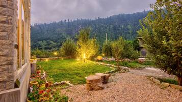 A stone building with a garden featuring a gravel path, wooden stools, and potted plants.