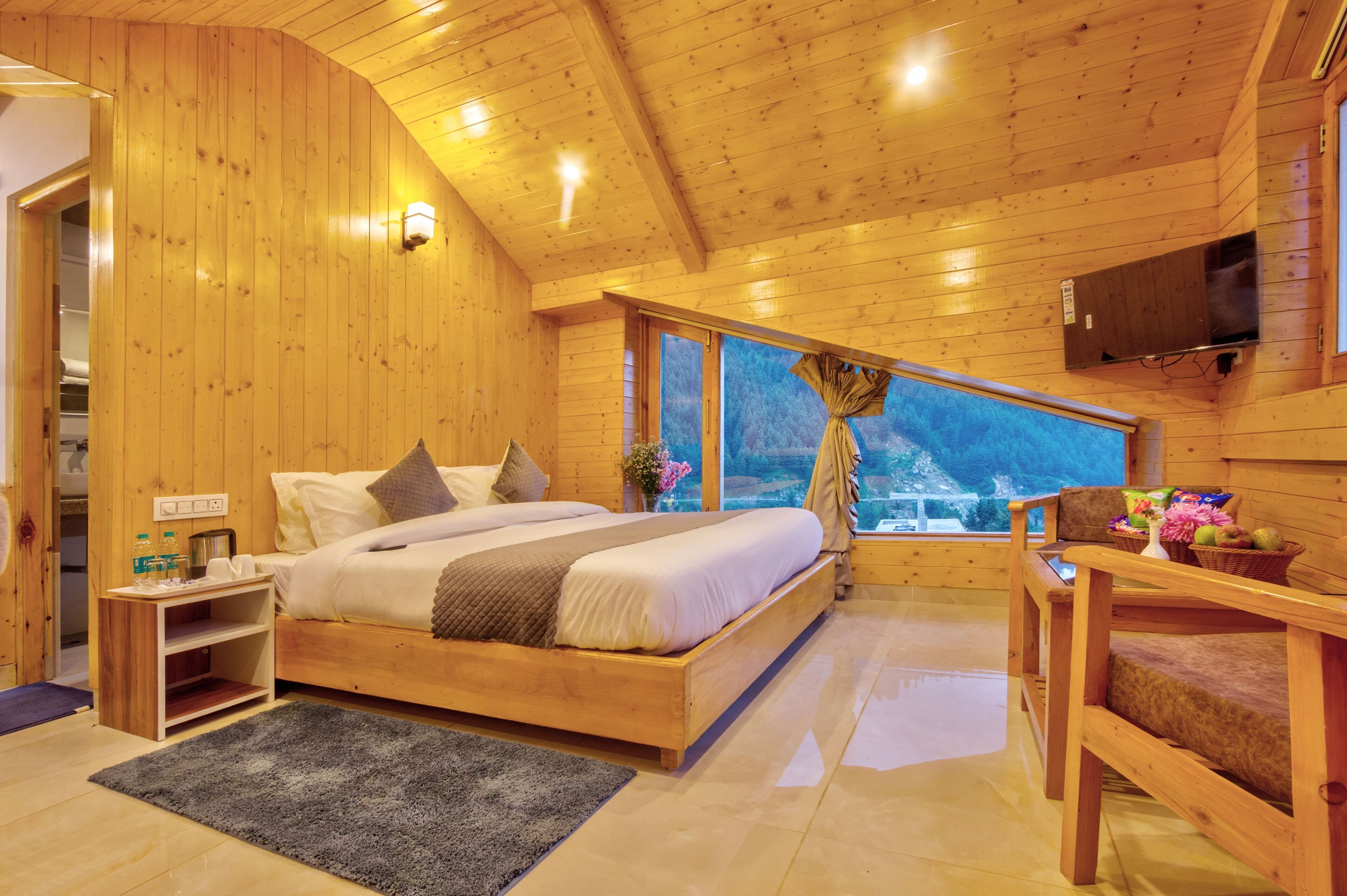 A wooden cabin bedroom with a bed, bedside table, and a window with a view.
