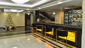 A bar area with a Christmas tree, a staircase, and a bar counter with bottles. - Macao Hotel (Yerevan)