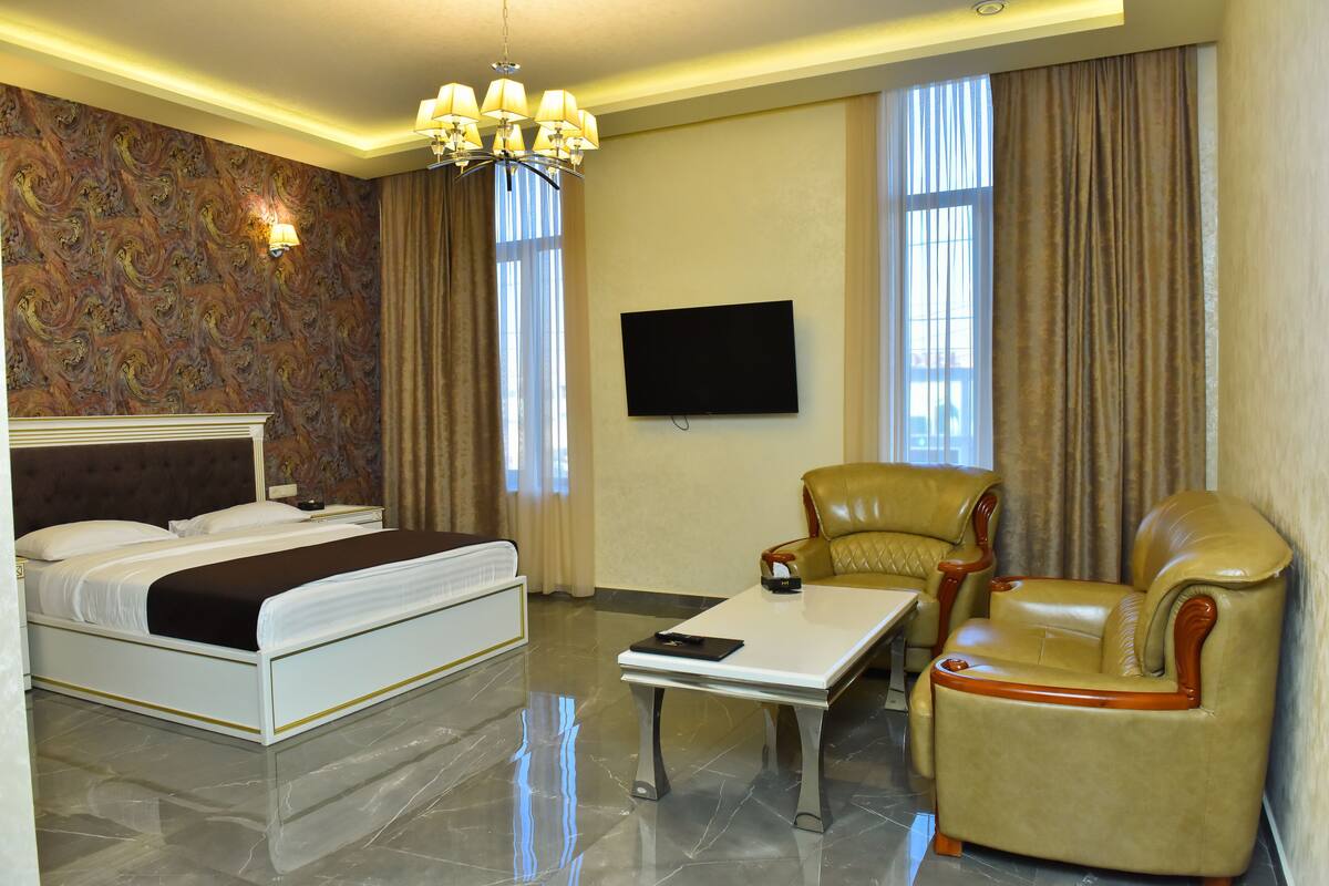 Ein Hotelzimmer mit einem Bett, einem Sofa, einem Couchtisch, einem Fernseher und einer Chandelier.