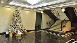 A grand lobby with a large Christmas tree, a staircase, and a chandelier. - Macao Hotel (Yerevan)