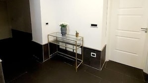 A room with a glass-top table, a white door, and dark flooring. - Yacht Club Angioino (Naples)