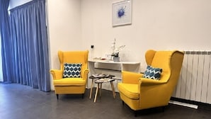 A modern living room with two yellow armchairs, a small side table, and a radiator. - Yacht Club Angioino (Naples)