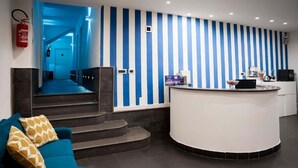 A reception area with a curved desk, a blue and white striped wall, and a staircase leading to another floor. - Yacht Club Angioino (Naples)