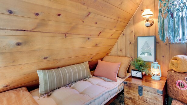 A cozy cabin interior with a wooden ceiling, a cushioned bench, a small table with a lantern, and macrame decorations. - 3 Mi to Big Bear Village: Charming Sugarloaf Cabin (Sugarloaf)