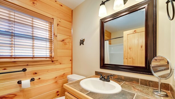 Un baño con paneles de madera, un inodoro, un lavabo y un espejo.
