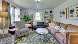 Un salon avec un ventilateur de plafond, un canapé, une table basse, un fauteuil et une lampe sur pied.