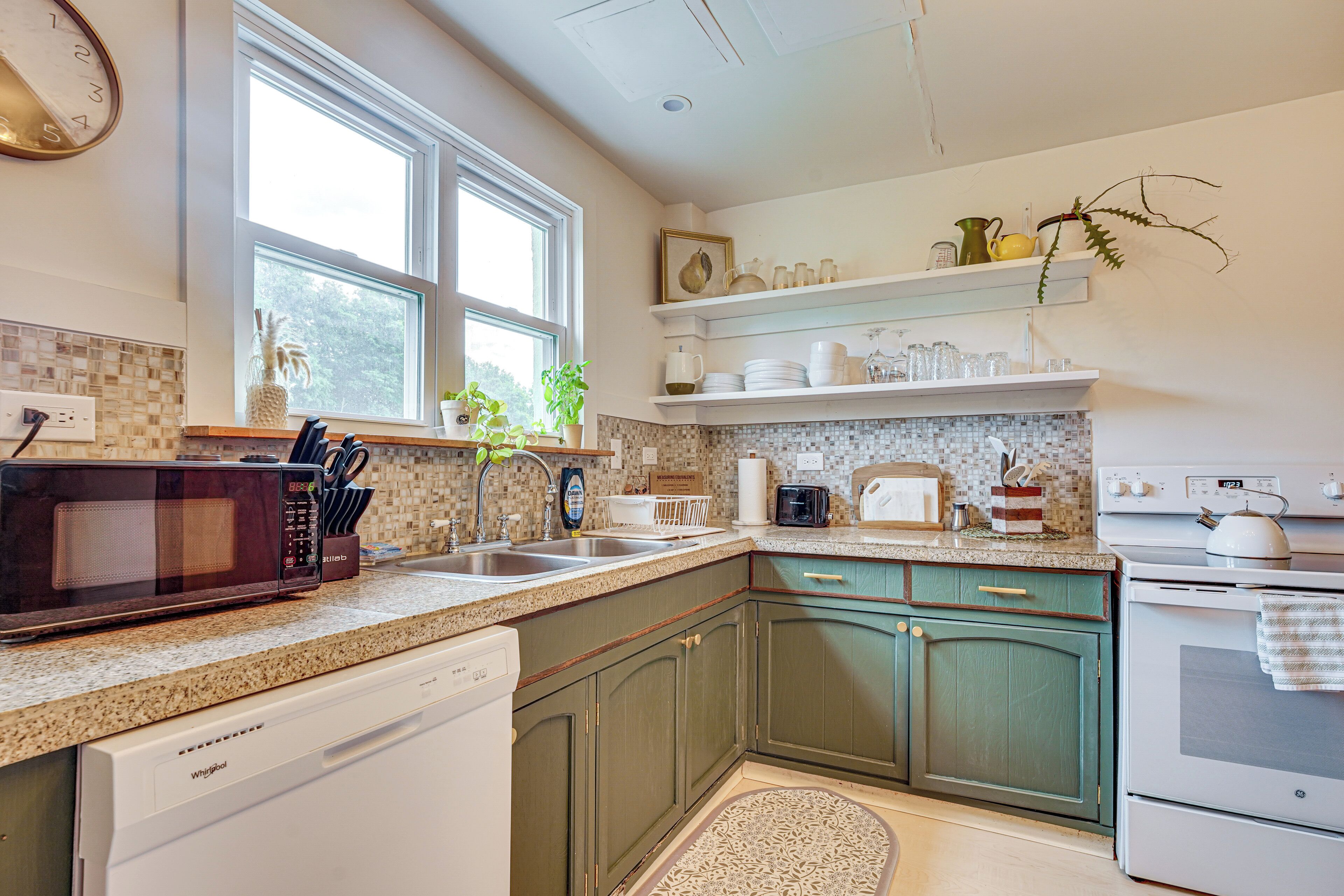 A kitchen with a dishwasher, microwave, sink, and stove.