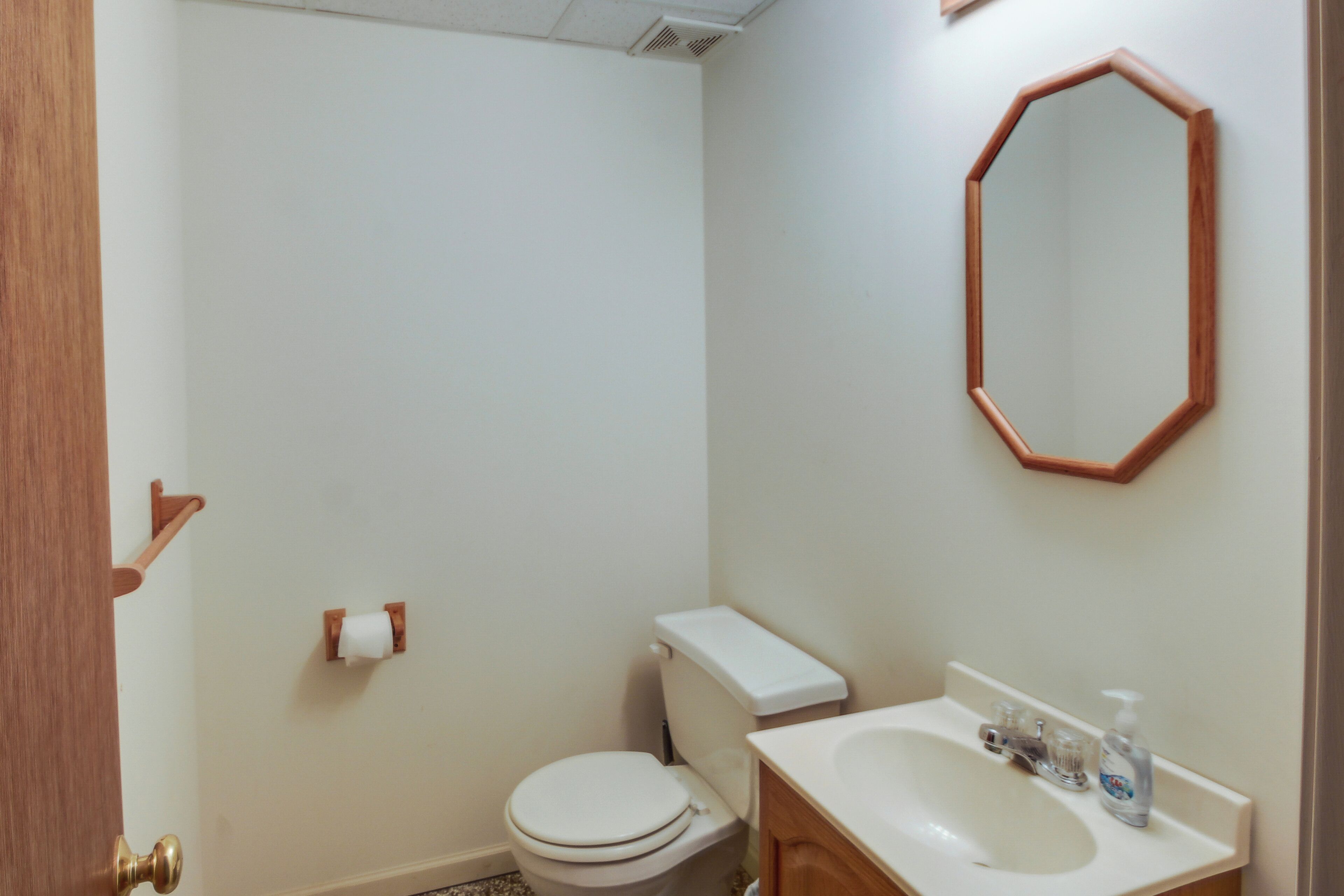 Een badkamer met toilet, wastafel en spiegel.