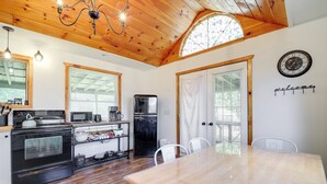 A kitchen with a wooden ceiling, a stove, microwave, refrigerator, and a dining table with chairs. - 'faith Cabin' in Cosby: Fire Pit + Covered Deck (Cosby)