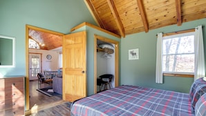 A bedroom with a plaid bedspread, wooden ceiling beams, a desk, and a chair. - 'faith Cabin' in Cosby: Fire Pit + Covered Deck (Cosby)