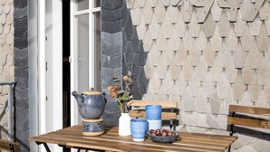 Una mesa al aire libre con un muro de piedra de fondo, un banco de madera y una puerta.