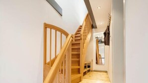 Una escalera de madera que sube a un segundo piso, con vistas a un baño y un espejo.