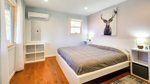 A bedroom with a bed, a window, an air conditioning unit, a wall-mounted shelf, and a deer artwork. - Serene Springfield Retreat on 6 Acres w/ Hot Tub! (Springfield)