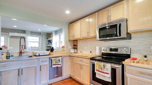 A kitchen with wooden cabinets, stainless steel appliances, and a tiled backsplash. - Serene Springfield Retreat on 6 Acres w/ Hot Tub! (Springfield)