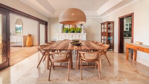 Un comedor amplio con una gran mesa de madera, sillas de mimbre y una lámpara colgante.