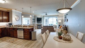 A modern kitchen with wooden cabinets, a dishwasher, and a dining area with a white table and chairs. - Boat Slip + Pool Access: Osage Beach Retreat (Osage Beach)