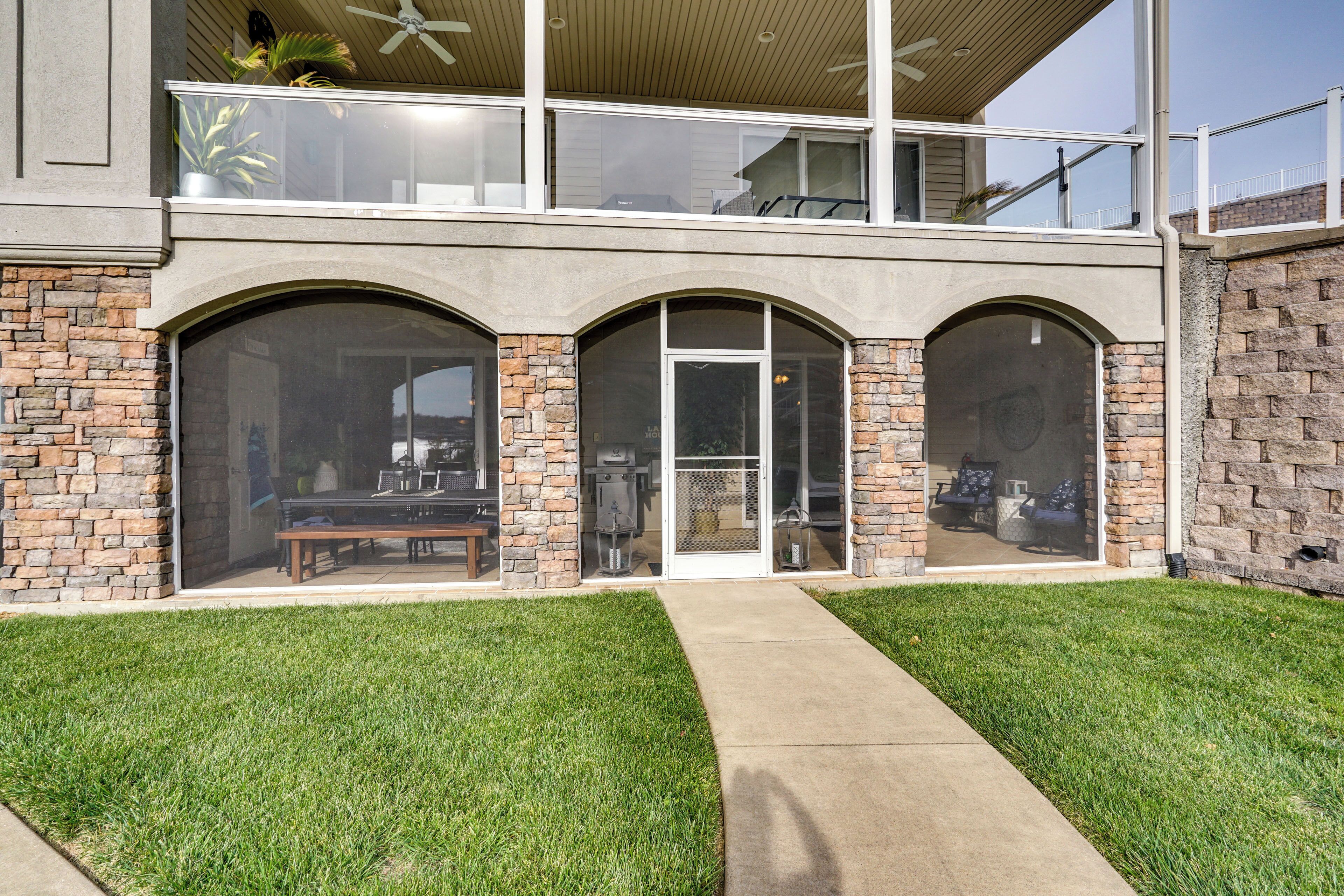 A two-story house with a stone facade, large arched windows, and a covered patio area.