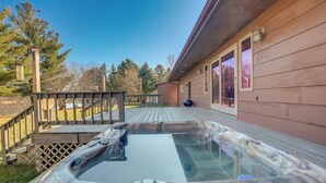 Un jacuzzi en una terraza de madera, con una cerca de madera y una casa al fondo.