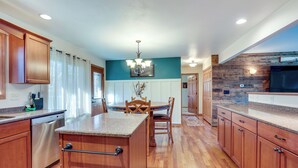 Una cocina con gabinetes de madera, encimera de granito, lavavajillas y una zona de comedor con mesa y sillas.