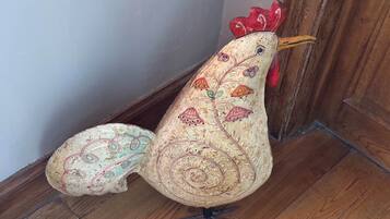 Une sculpture décorative représentant un coq, placée sur un plancher en bois près d’une porte.