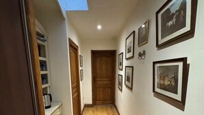 A hallway with wooden flooring, a skylight, and framed pictures on the walls. - La Chambre Rouge (ECHINGHEN)