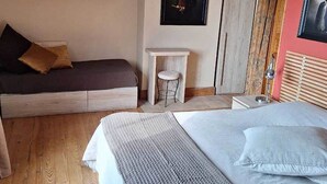 A bedroom with a large bed, a small stool, a wooden floor, and a chandelier. - La Chambre Rouge (ECHINGHEN)