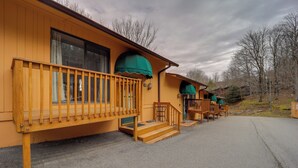 A row of wooden cabins with green awnings, wooden railings, and a gravel driveway. - Beech Mountain Condo w/ Community Pool & Game Room (Banner Elk)