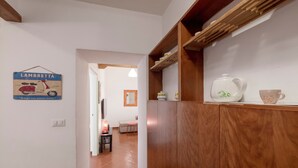 A hallway with a sign reading "Lambretta," a wooden cabinet with kitchenware, and a tiled floor. - Opera House (Rome)