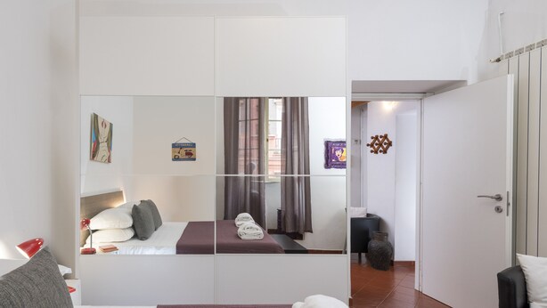A hotel room with a bed, a mirror, a wardrobe, a desk, and a chair. - Opera House (Rome)