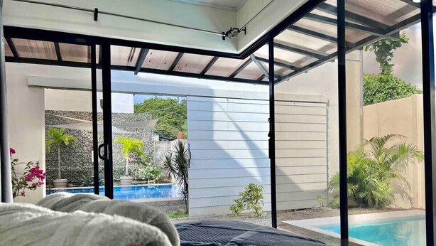 Une chambre avec un lit, une serviette et une vue sur une piscine et un jardin.