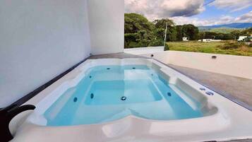 A hot tub in an outdoor setting with a view of greenery and hills in the background.