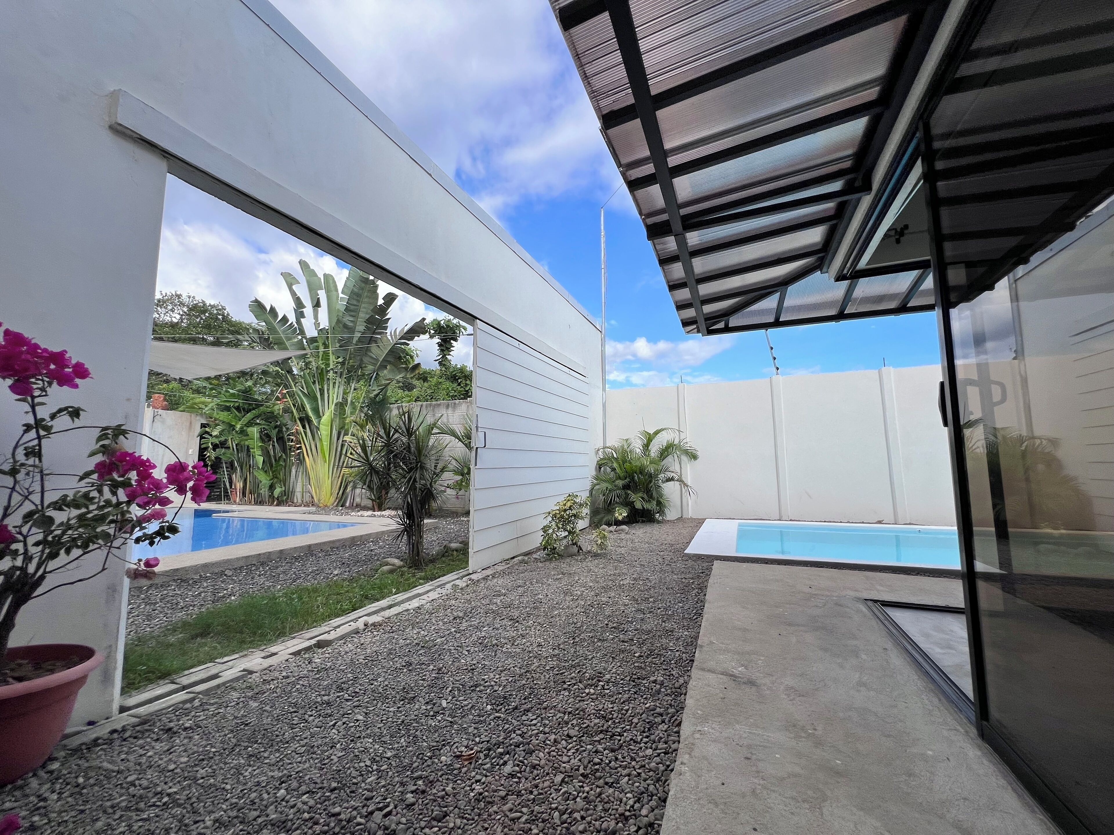 Un espace extérieur moderne doté d’une piscine, d’un sol en gravier et de plantes en pot.