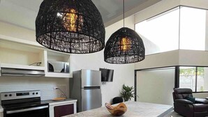 Une cuisine moderne dotée d’un grand îlot central, de luminaires suspendus et d’un coin repas avec des chaises.