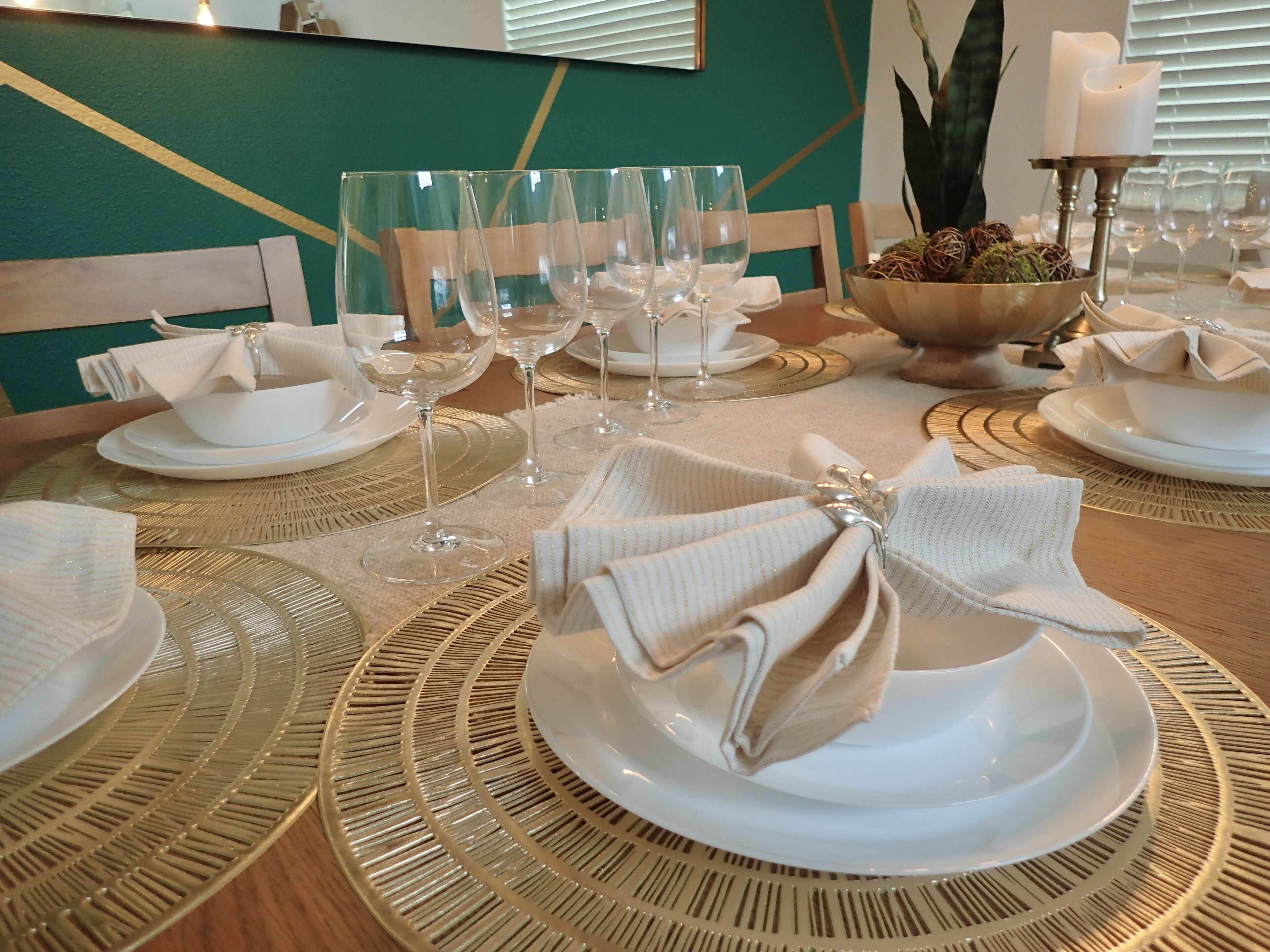 Ein Tisch ist für ein formelles Abendessen gedeckt, mit weißen Tellern, Gläsern und einer Tischdekoration.