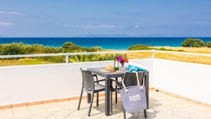 Een terras met een tafel en stoelen met uitzicht op de kust.