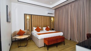 A modern hotel room with a bed, a sofa, a bench, a desk, and a large window with curtains. - Bayview Resorts And Hotels Lekki (Lekki)